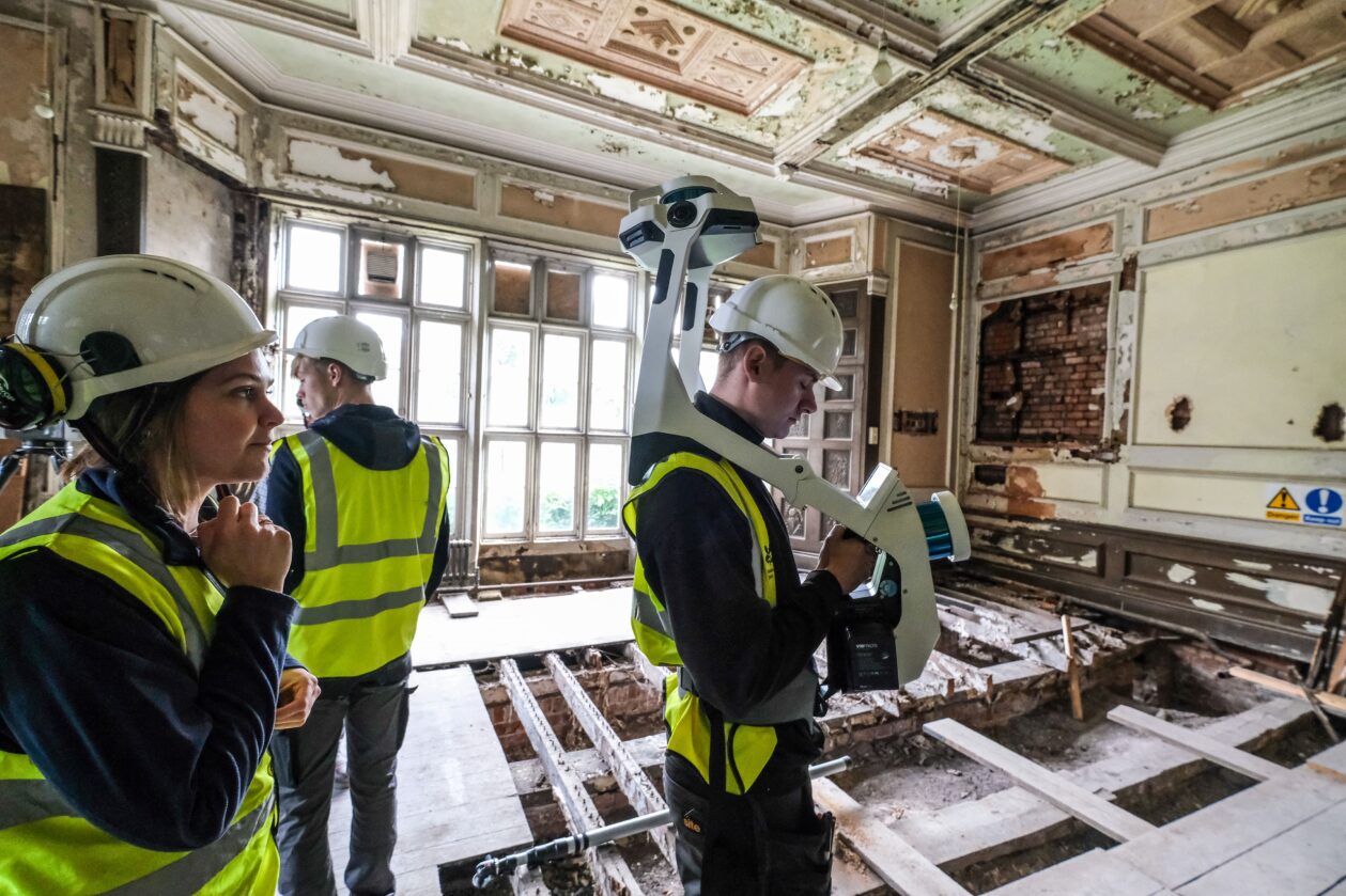 Three people using equipment in a room of disrepair. 