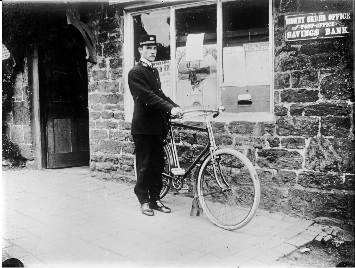 A postman and his bicycle outside of the post office. 