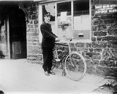 A postman and his bicycle outside of the post office. 