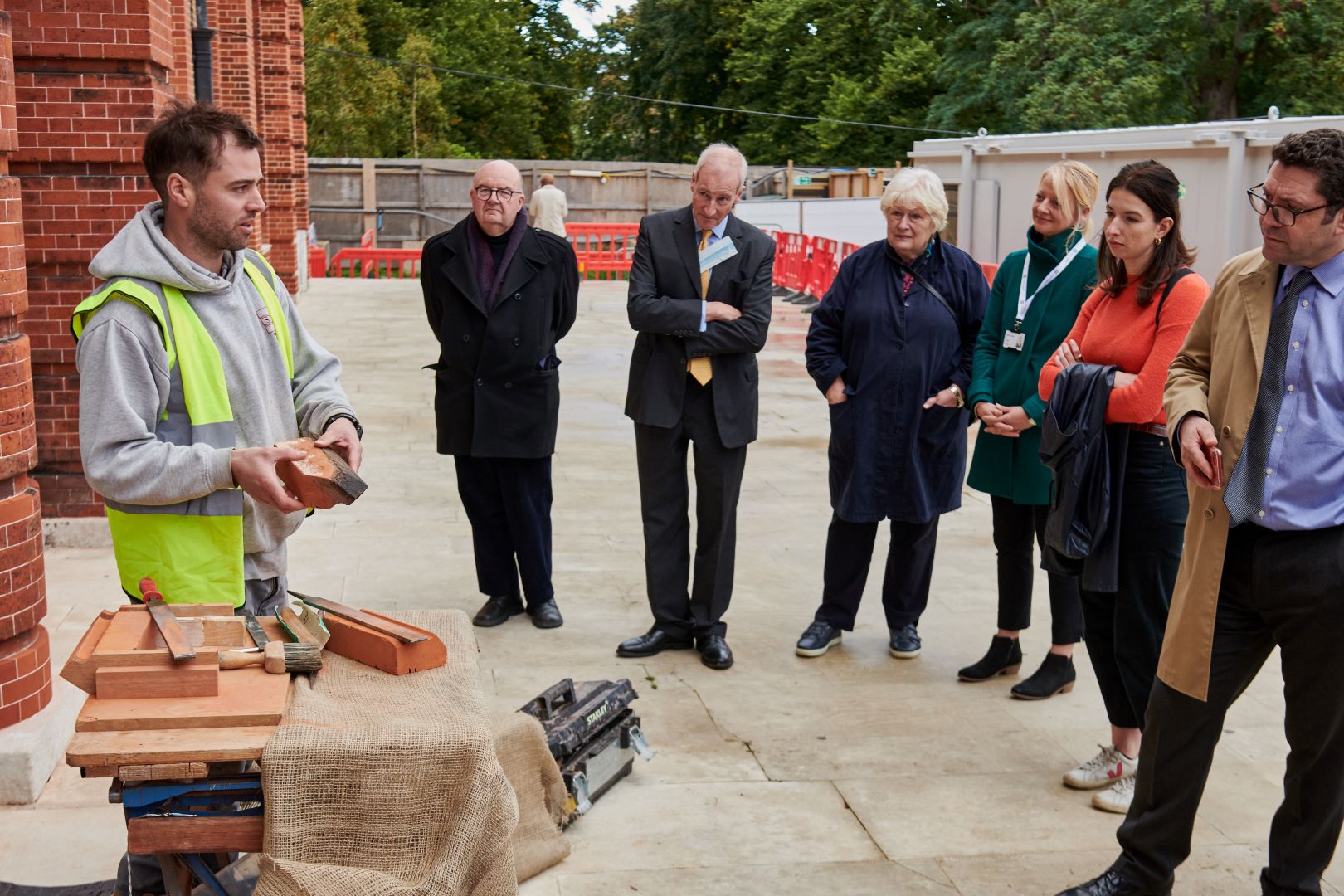 Six people listening to a man holding bricks.